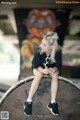 A woman sitting on top of a skateboard holding a cell phone.