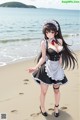 A woman in a maid outfit standing on a beach.