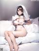 A woman in a white dress is sitting on a bed.