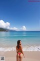 A woman in a red bikini standing on a beach.