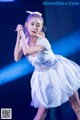 A woman in a white dress dancing on a stage.