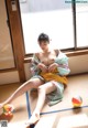 A woman in a kimono sitting on the floor next to a window.