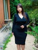 A woman in a black dress standing in front of a building.