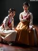 A couple of women sitting next to each other on a wooden floor.