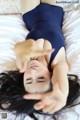 A woman in a blue leotard laying on a bed.