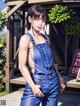 A woman in overalls is posing for a picture.