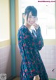 A woman in a blue dress standing in a bathroom.