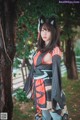 A woman in a kimono standing next to a tree.