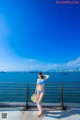 A woman in a blue bikini standing by the water.