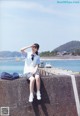 A woman sitting on a concrete wall by the water.