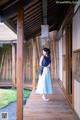 A woman in a blue and white dress standing on a wooden walkway.