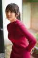 A woman in a red sweater posing for a picture.