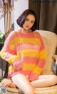 A woman sitting on a chair wearing a pink and yellow sweater.